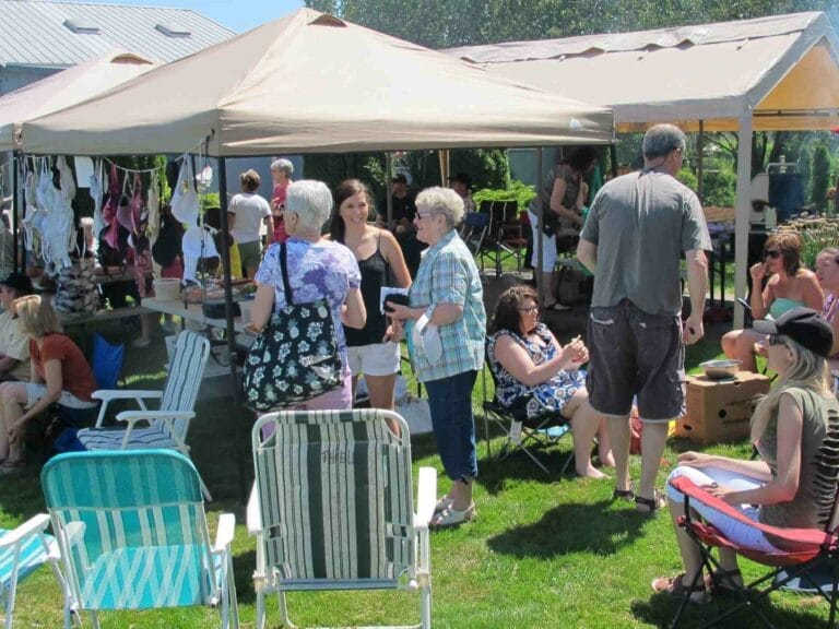 A group of people standing in a lawn with chairs and a tent
