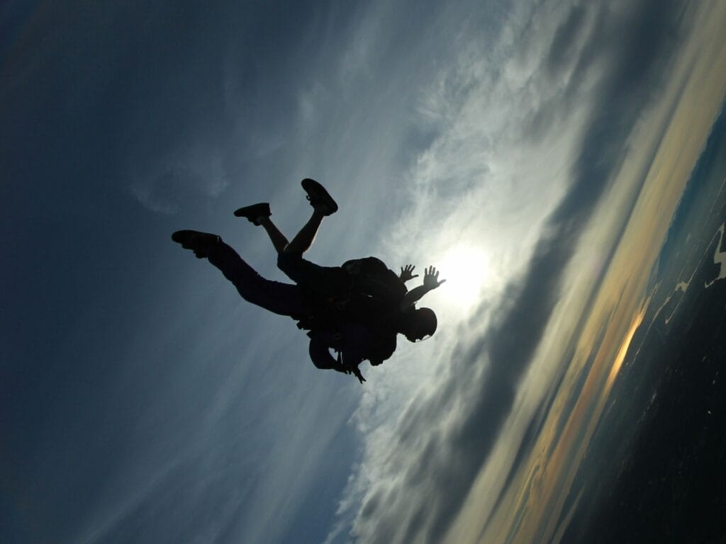 a silhouette of a person skydiving with another person