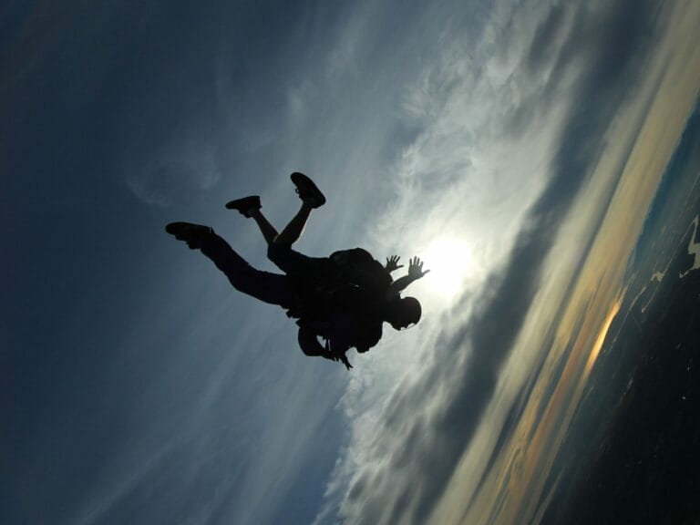 a silhouette of a person skydiving with another person