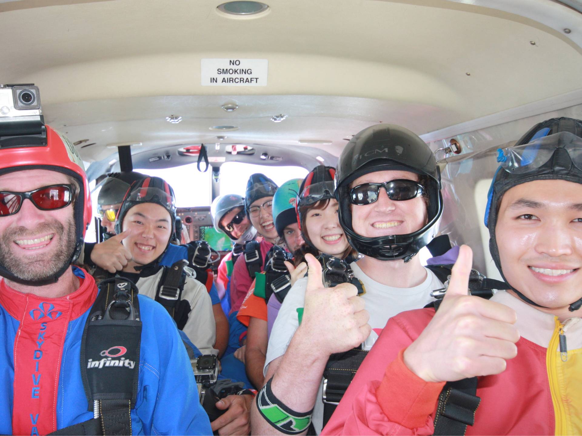 A group of passengers in an airplane, smiling and giving thumbs up gestures, showing approval and positivity during the flight